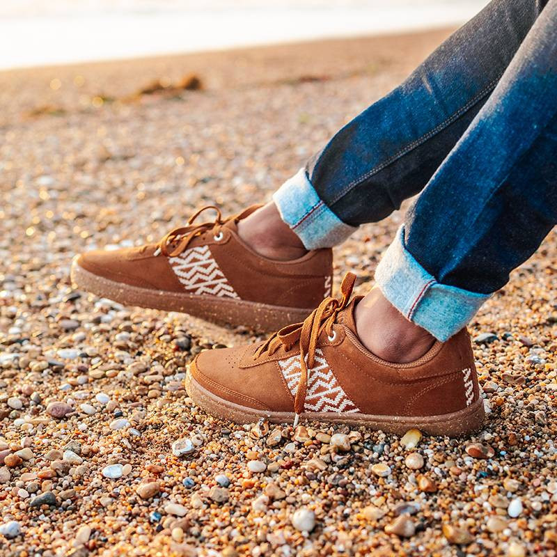 Modèle portant une paire de baskets en daim avec des motifs ethniques artisanaux, lookbook. Saigon Suede Camel.