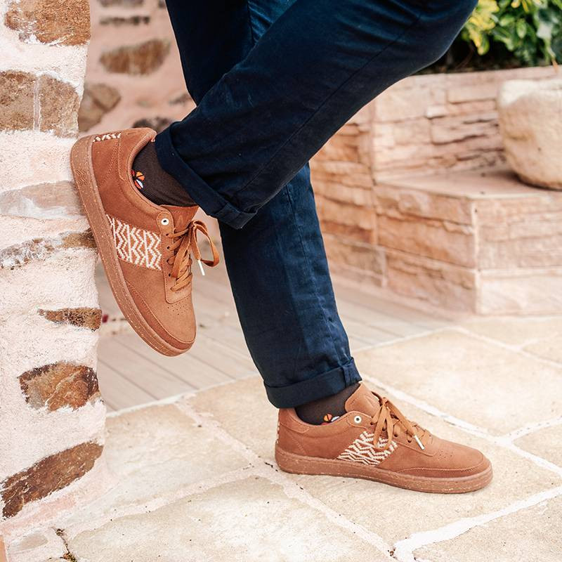 Modèle portant une paire de baskets en daim avec des motifs ethniques artisanaux, lookbook. Saigon Suede Camel.