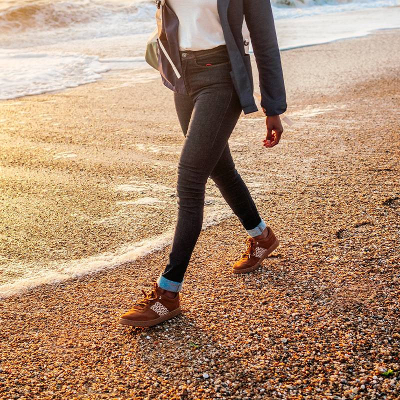 Modèle portant une paire de baskets en daim avec des motifs ethniques artisanaux, lookbook. Saigon Suede Camel.