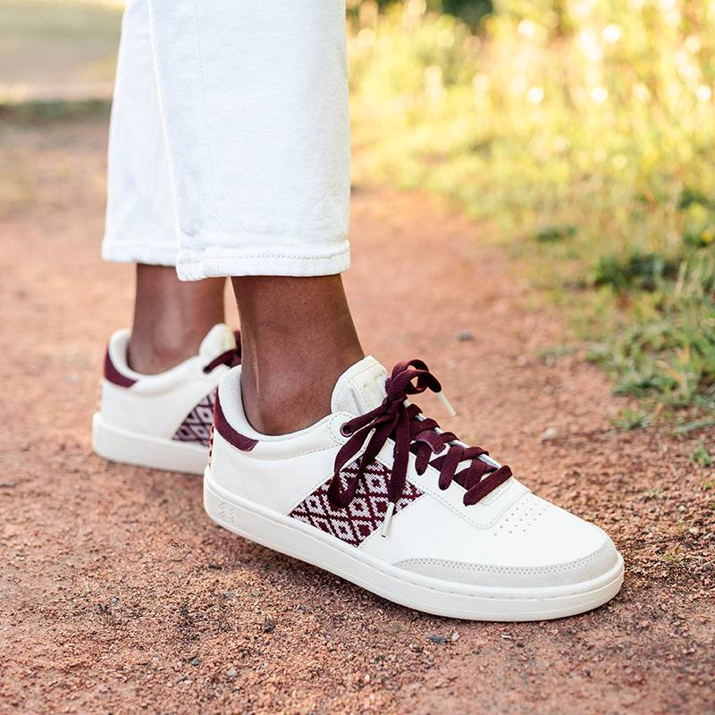 Modèle portant une paire de baskets en cuir avec des motifs ethniques artisanaux, lookbook. Saigon Classique burgundy.