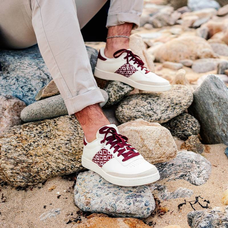 Modèle portant une paire de baskets en cuir avec des motifs ethniques artisanaux, lookbook. Saigon Classique burgundy.