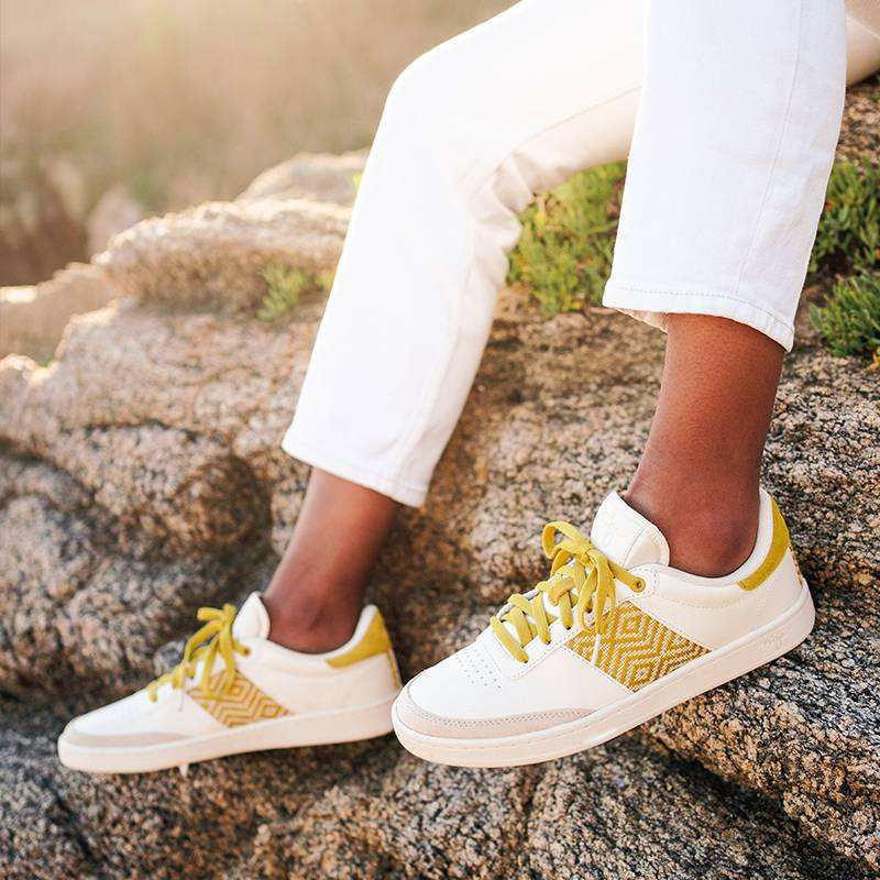 Modèle portant une paire de baskets en cuir avec des motifs ethniques artisanaux, lookbook. Saigon Classique Yellow.