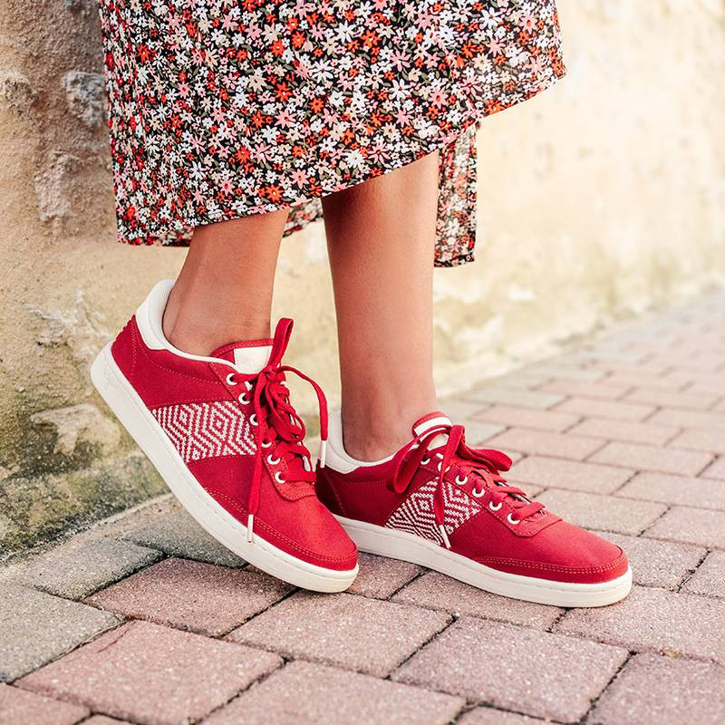 Modèle portant une paire de baskets en cuir avec des motifs ethniques artisanaux, lookbook. Saigon Canvas Red.