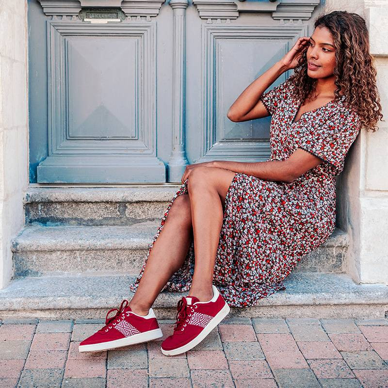 Modèle portant une paire de baskets en cuir avec des motifs ethniques artisanaux, lookbook. Saigon Canvas Red.