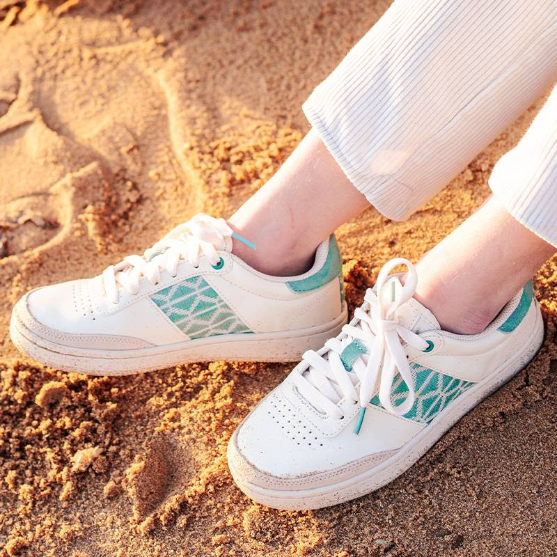 Modèle portant une paire de baskets en cuir avec des motifs ethniques artisanaux, lookbook. Saigon Classique Mint.