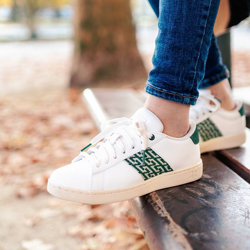 Modèle portant une paire de baskets en cuir avec des motifs ethniques artisanaux, lookbook. Ho Tay Classique Green.