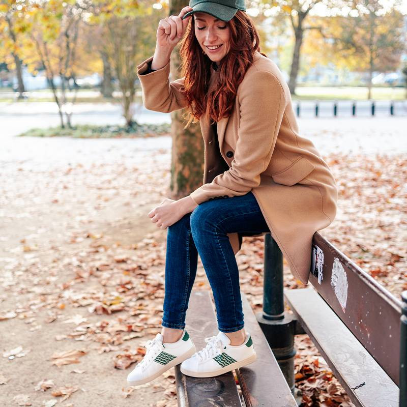 Modèle portant une paire de baskets en cuir avec des motifs ethniques artisanaux, lookbook. Ho Tay Classique Green.