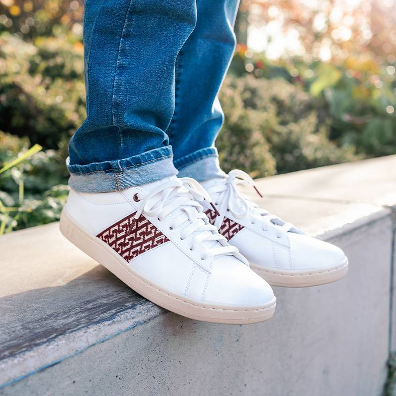 Modèle portant une paire de baskets en cuir avec des motifs ethniques artisanaux, lookbook. Ho Tay Burgundy.