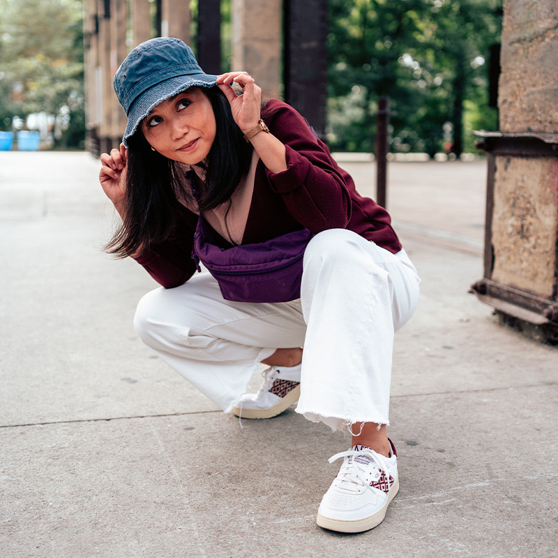 Modèle portant une paire de baskets en cuir avec des motifs ethniques artisanaux, lookbook. Hue Classique Burgundy.