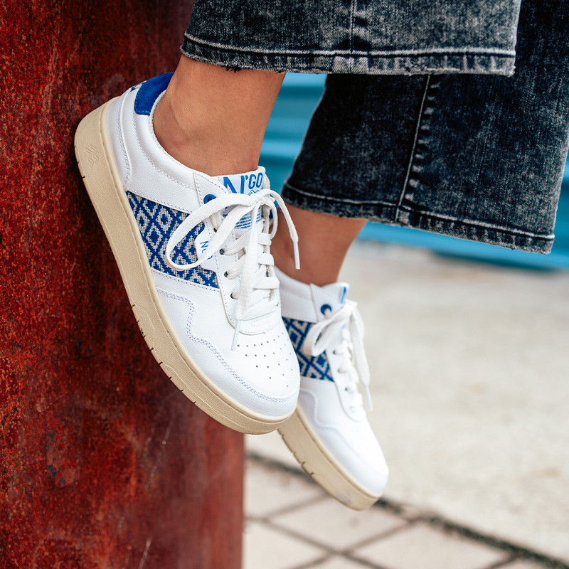 Modèle portant une paire de baskets en cuir avec des motifs ethniques artisanaux, lookbook. Hue Classique Ocean blue.