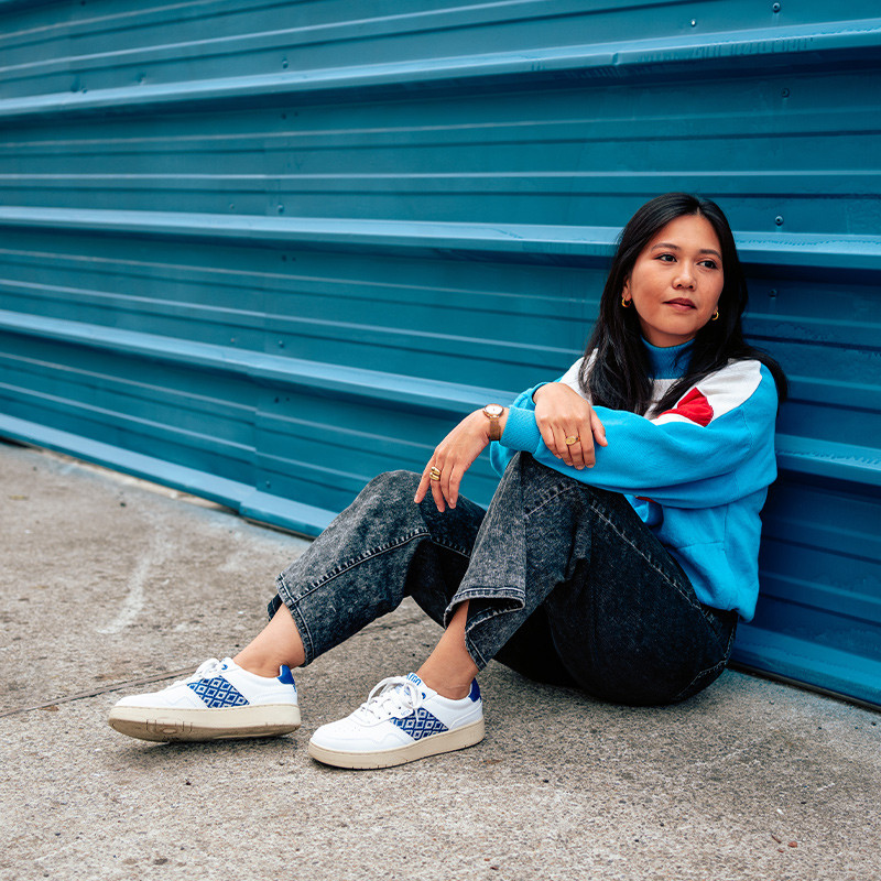 Modèle portant une paire de baskets en cuir avec des motifs ethniques artisanaux, lookbook. Hue Classique Ocean blue.