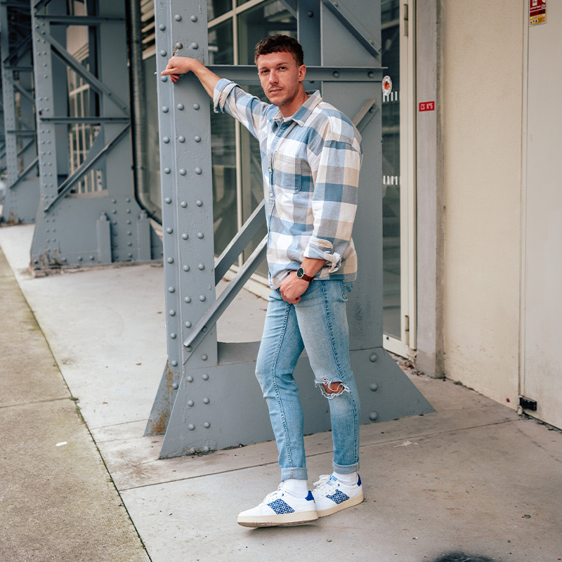 Modèle portant une paire de baskets en cuir avec des motifs ethniques artisanaux, lookbook. Hue Classique Ocean blue.