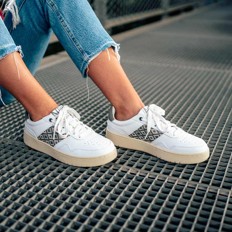 Modèle portant une paire de baskets en cuir avec des motifs ethniques artisanaux, lookbook. Hue Classique Grey.