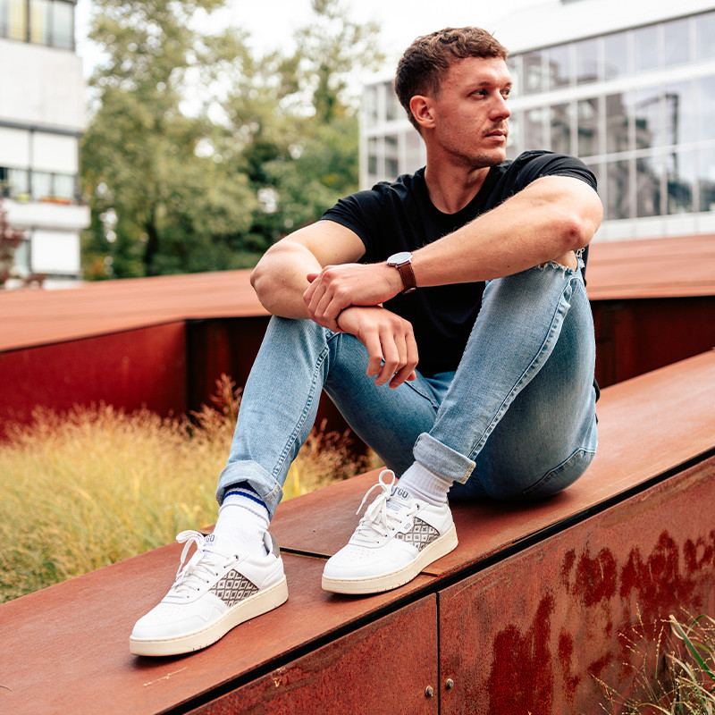 Modèle portant une paire de baskets en cuir avec des motifs ethniques artisanaux, lookbook. Hue Classique Grey.