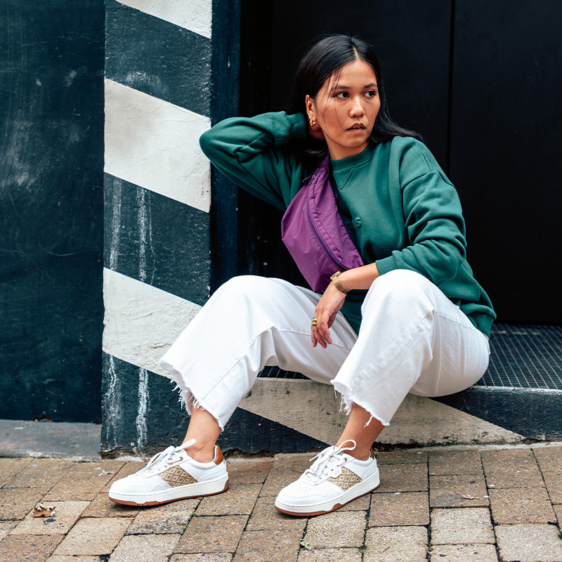 Modèle portant une paire de baskets en cuir avec des motifs ethniques artisanaux, lookbook. Hue Classique Sand Cognac.