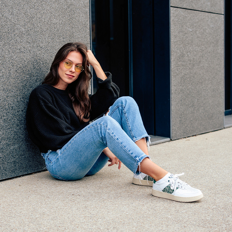 Modèle portant une paire de baskets en cuir avec des motifs ethniques artisanaux, lookbook. Hue Classique Green.