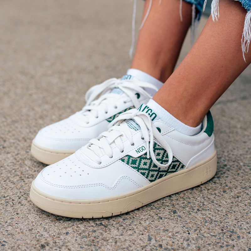 Modèle portant une paire de baskets en cuir avec des motifs ethniques artisanaux, lookbook. Hue Classique Green.