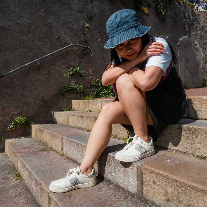 Modèle portant une paire de baskets en cuir avec des motifs ethniques artisanaux, lookbook. Saigon Classique Olive.