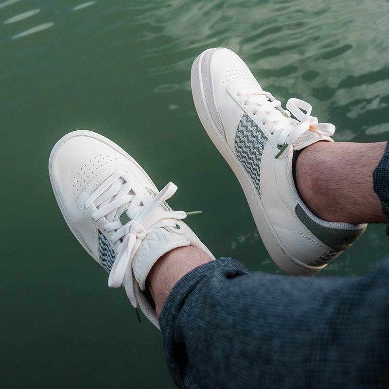 Modèle portant une paire de baskets en cuir avec des motifs ethniques artisanaux, lookbook. Saigon Classique Olive.