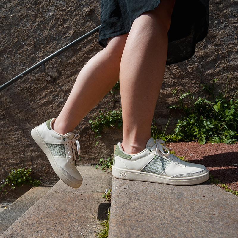 Modèle portant une paire de baskets en cuir avec des motifs ethniques artisanaux, lookbook. Saigon Classique Olive.