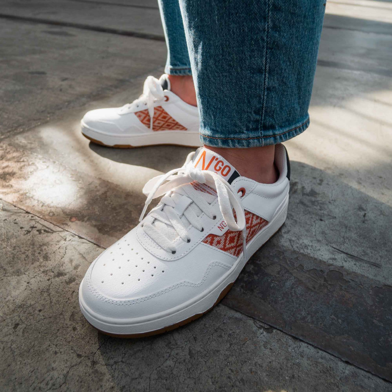 Modèle portant une paire de baskets en cuir avec des motifs ethniques artisanaux, lookbook. Hue Classique Rust Navy.