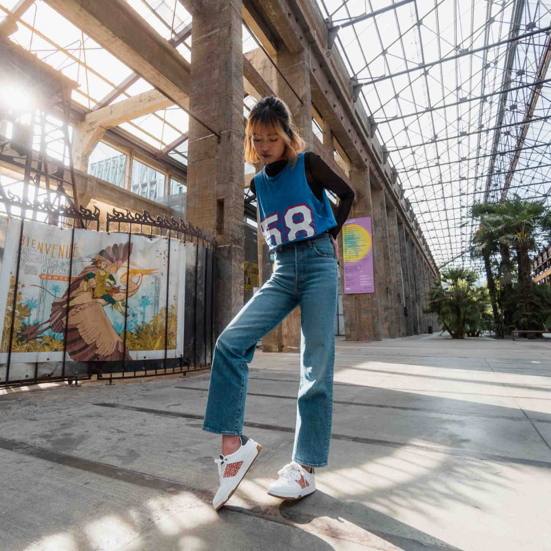 Modèle portant une paire de baskets en cuir avec des motifs ethniques artisanaux, lookbook. Hue Classique Rust Navy.