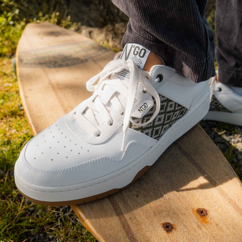 Modèle portant une paire de baskets en cuir avec des motifs ethniques artisanaux, lookbook. Hue Classique Khaki Peach.