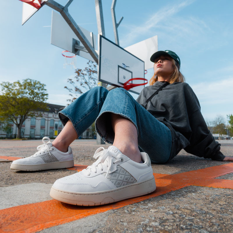 Modèle portant une paire de baskets en cuir avec des motifs ethniques artisanaux, lookbook. Hue Classique White.