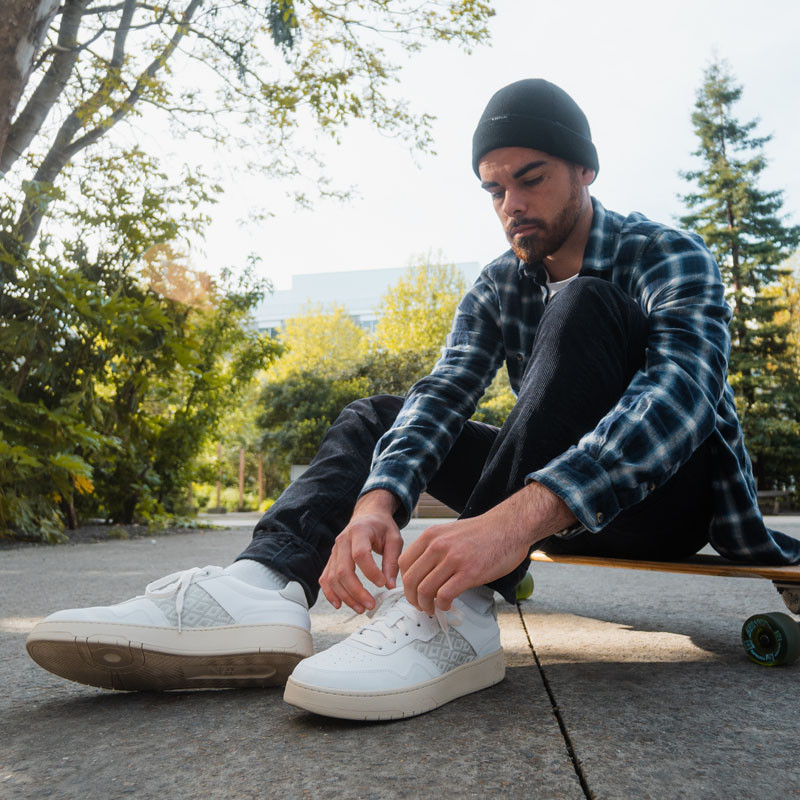 Modèle portant une paire de baskets en cuir avec des motifs ethniques artisanaux, lookbook. Hue Classique White.