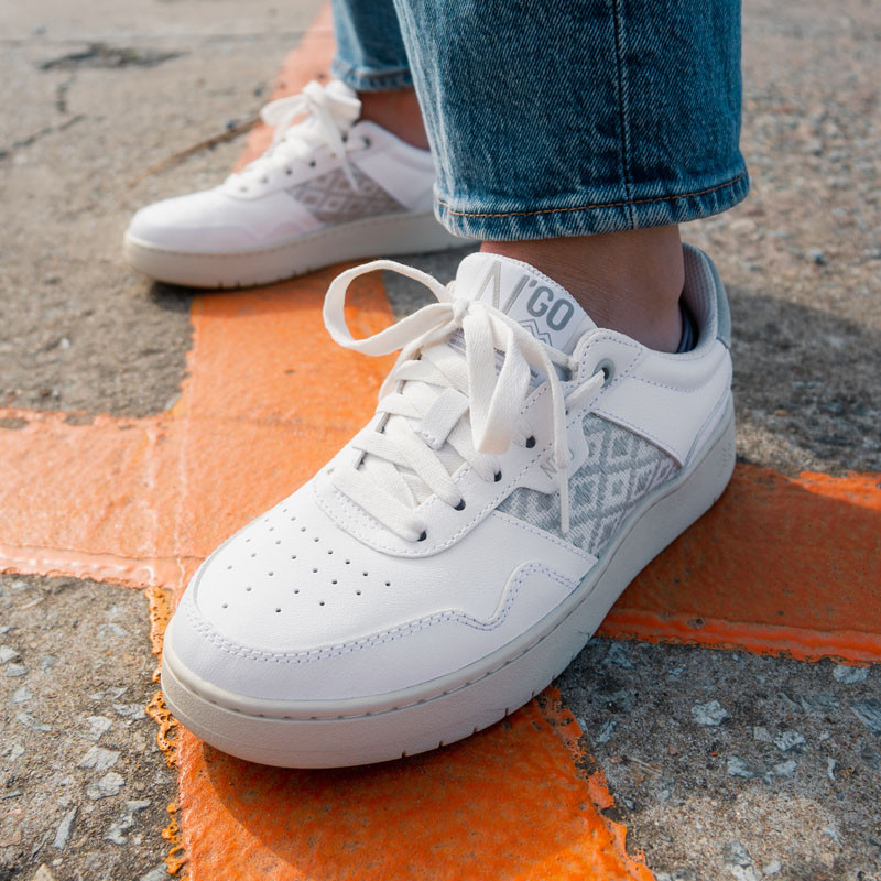 Modèle portant une paire de baskets en cuir avec des motifs ethniques artisanaux, lookbook. Hue Classique White.