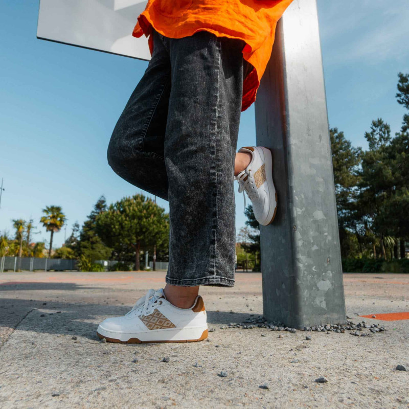 Modèle portant une paire de baskets en cuir avec des motifs ethniques artisanaux, lookbook. Hue Classique Sand Cognac.