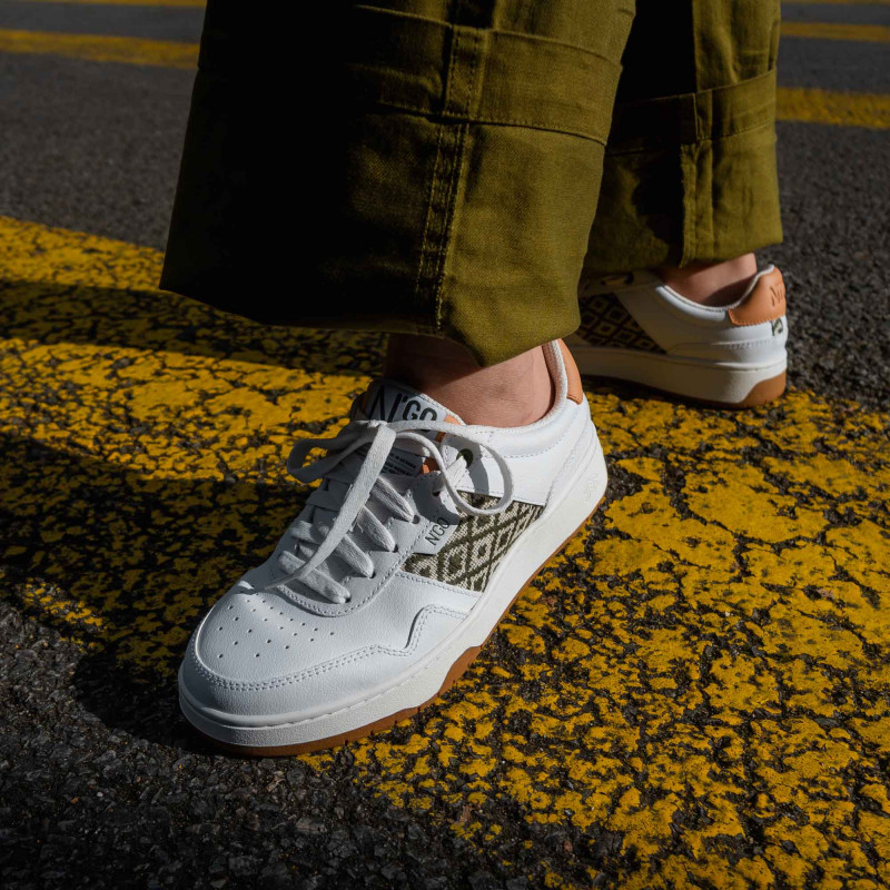 Modèle portant une paire de baskets en cuir avec des motifs ethniques artisanaux, lookbook. Hue Classique Khaki Peach.