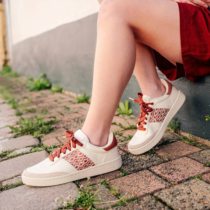 Modèle portant une paire de baskets en cuir avec des motifs ethniques artisanaux, lookbook. Saigon Classique Terracotta.