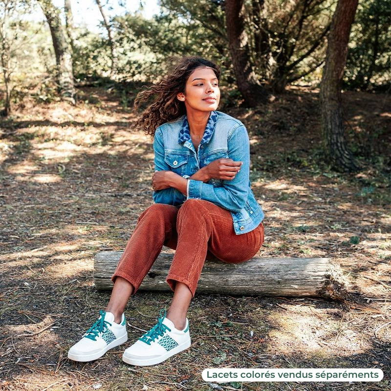 Modèle portant une paire de baskets en cuir avec des motifs ethniques artisanaux, lookbook. Saigon Classique Green.