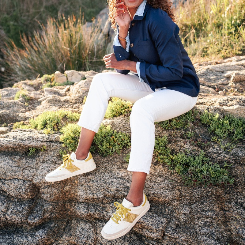 Femme portant une paire de baskets en cuir avec des motifs ethniques artisanaux, lookbook. Saigon Classique Yellow.