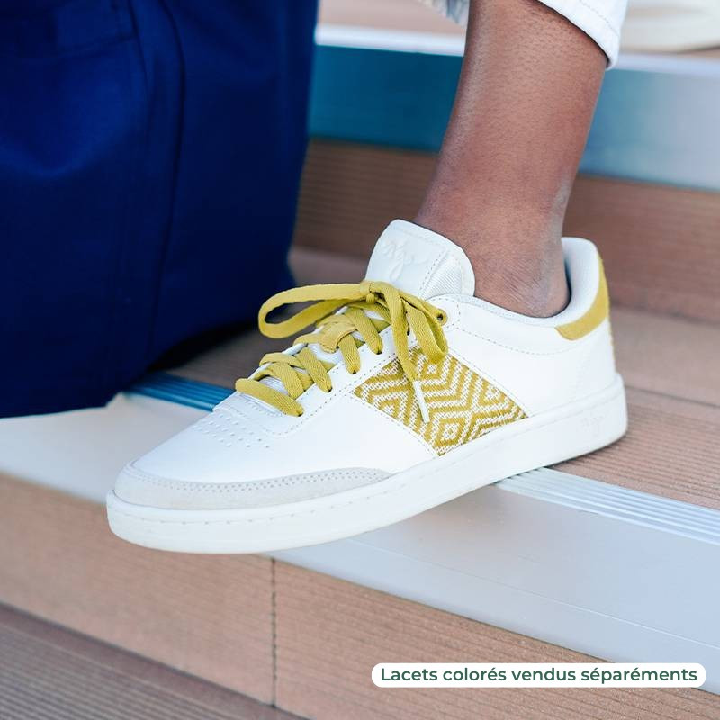 Modèle portant une paire de baskets en cuir avec des motifs ethniques artisanaux, lookbook. Saigon Classique Yellow.